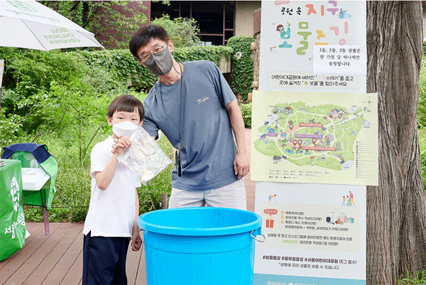 서울 광진구 서울어린이대공원에서 지난 23~24일 열린 '보물줍깅'에 참여한 어린이가 아버지와 주운 쓰레기를 통 안에 넣고 있다. (사진=풀무원)